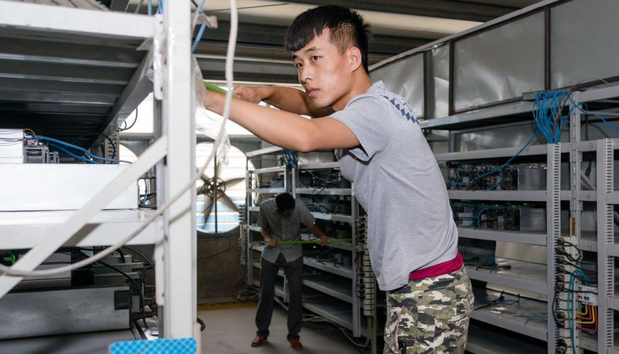 A miner inspects a row of mining rigs, highlighting the importance of hardware maintenance.